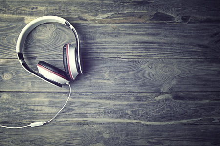 Minimalist photo of earphones with copy space. white dj headphones with cable on old woodenl backdrop, flat lay top view. Music conceptの写真素材