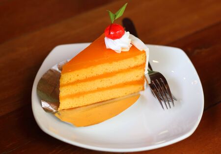 Orange layer cake on white plate put on wood table.の写真素材