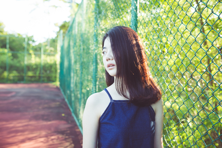 beautiful asian girl on tennis court after playing tennis with friend dressing like sport girl for sport, healthy, exercise, use purpose with artificial sun flares and color shiftの写真素材