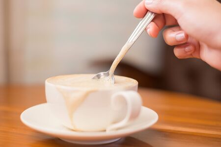 coffee cup with hand on wood table, soft and selective focusの写真素材