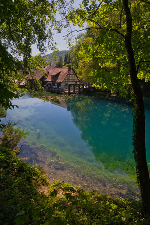 Germany, Blaubeuren - August 20, 2023: The Blautopf is a spring in a karst environment with blue water and a hammer mill.のeditorial素材