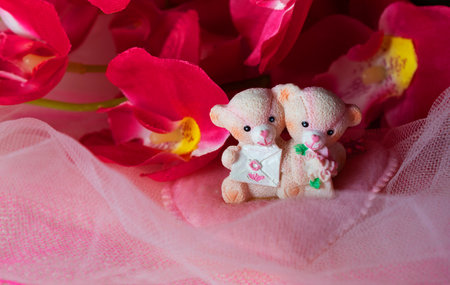 souvenir teddy bears on a pink textile background with hearts and flowers for Valentine's dayの写真素材