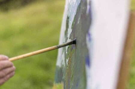 Drawing oil paintings of a natural landscape on a white cardboard. Happiness, hobbies.の写真素材
