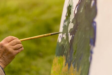 Drawing oil paintings of a natural landscape on a white cardboard. Happiness, hobbies.の写真素材
