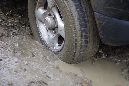 Car stuck, car wheel in a dirty puddle, rough terrain.