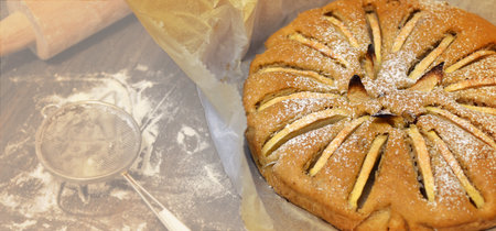 home made apple pie removed from the oven on work table with flour and powdered sugar.の写真素材