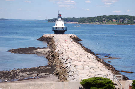 lighthouse on a jetty in portland harborの写真素材