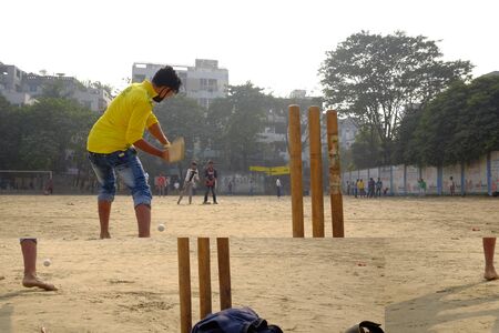 Dhaka, bangladesh - January 2018 - Big group of young people playing cricket in the streets of...
