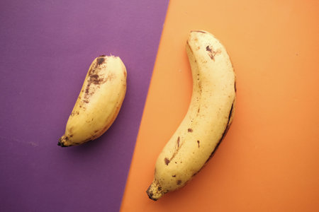 top view of big and small banana on color background