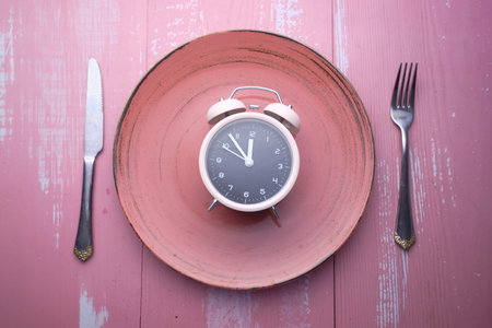 alarm clock on plate on pink background