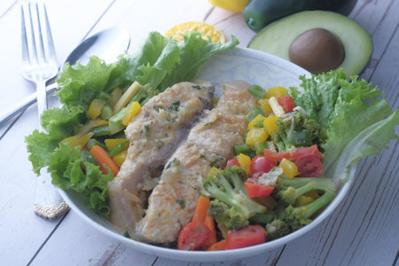 closeup of fish fillet and salad on plate.