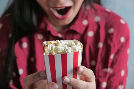 young women with red dress eating popcorn, closeup .の写真素材