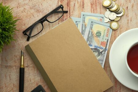 notepad, eyeglass, coin and tea on table,の写真素材