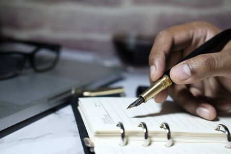 Close up of man hand writing on notepad at office desk.の写真素材