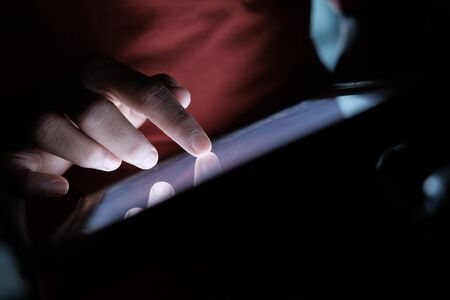young man use digital tablet at night, close up.の写真素材