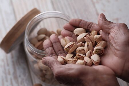 close up of pistachios on women hand on table.の写真素材
