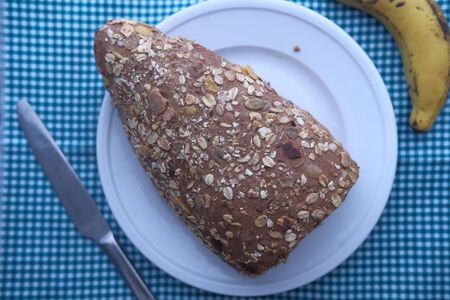 top view of brown bread on plate and banana on table.の写真素材