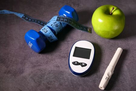 Close up of diabetic measurement tools and apple on tableの写真素材