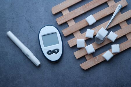 thigh angle view of diabetic measurement tools and sugar cube on tableの写真素材