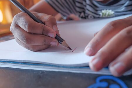 close up of child boy drawing on paper with color pencilの写真素材