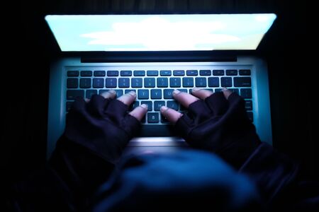 hooded hacker sealing data from laptop.の写真素材