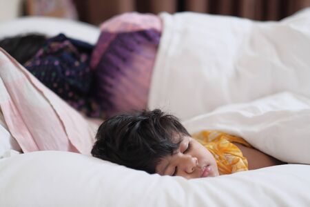 baby child sleeping with mother on bedの写真素材