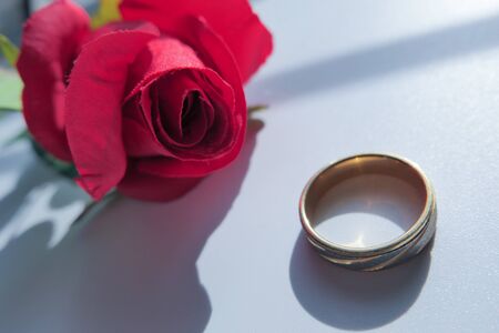 close up of wedding ring and rose flower on table.の写真素材