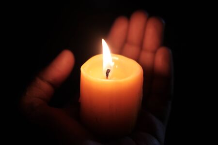 burning candle on women hand at night , close up .の写真素材