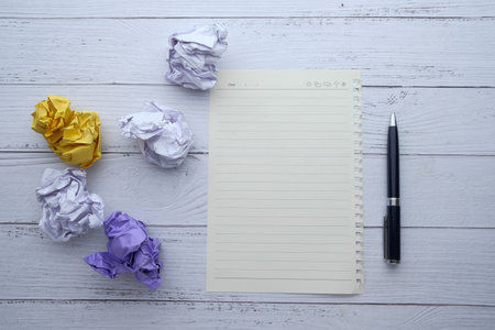 top view of crumple paper ball and notepad on table