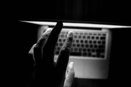 hooded hacker sealing data from laptop.の写真素材