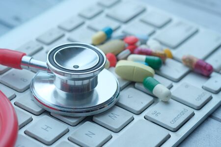 Close up of pills, stethoscope on keyboard.の写真素材