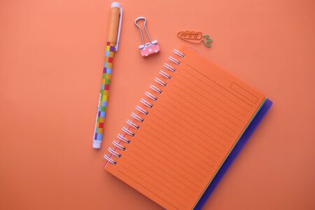 top view of notepad and pen on orange background.の写真素材