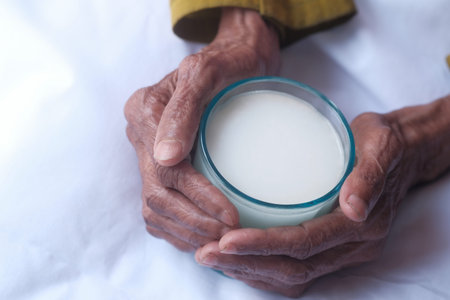 Senior woman's hands holding a glass of milk.