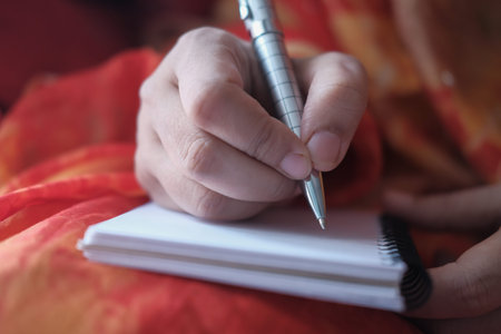 Close up hand of young woman with pen writing on notebook 