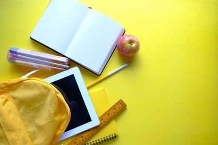 top view of school suppliers on yellow background