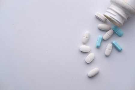 Close up of pills spilling from container on orange background