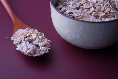 Close up of fresh oats on spoon on color background