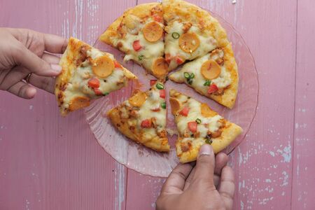 Hands taking pizza slices from plate, top view.の写真素材