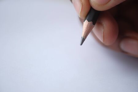 close of man hand writing with pencil on paper.の写真素材
