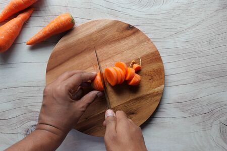 top view of man hand cutting carrot on chopping boardの写真素材