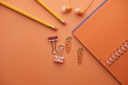 Close up of orange color notepad and pencil on orange backgroundの写真素材
