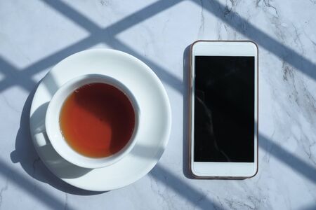 top view of smart phone and tea on table at morningの写真素材