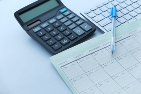 Close up of planner, pen and calculator on table.