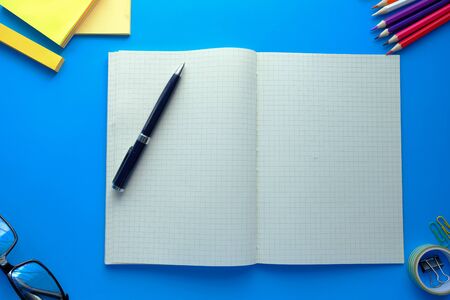 top view of open notepad and pencils on blue backgroundの写真素材