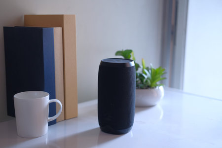Close up of smart speaker on table against wall.