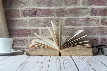 close up of open book and tea cup on tableの写真素材