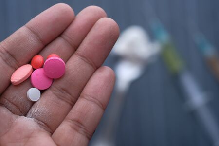 top view of pills on man hand and syringe on tableの写真素材