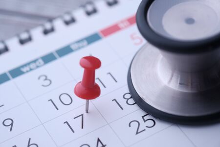 Regular medical examination concept, black stethoscope and push pin on calendar backgroundの写真素材