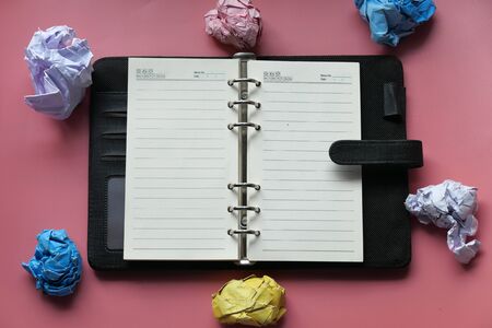 top view of crumbled paper ball and notepad on tableの写真素材