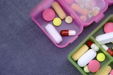 close up of pills and capsules in a pill box on black backgroundの写真素材